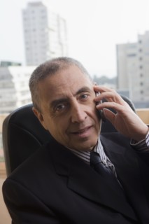 Portrait of Hispanic businessman talking on cell phone in office