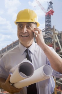 Hispanic architect talking on cell phone at construction site