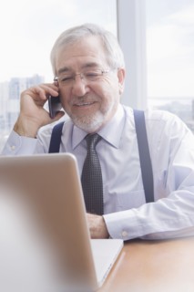 Hispanic businessman talking on cell phone at desk