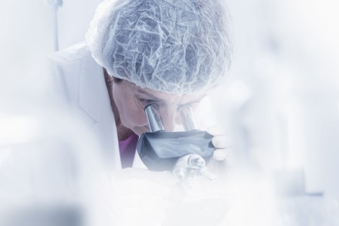 Hispanic scientist using microscope in lab