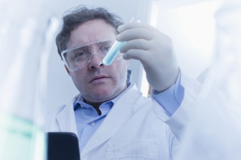 Hispanic scientist examining test tube in lab