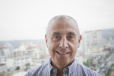Hispanic senior man smiling near scenic view of cityscape