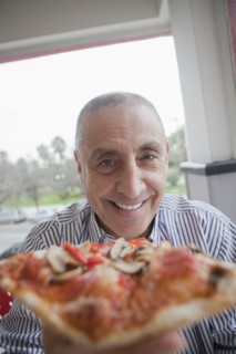 Hispanic senior man sharing slice of pizza