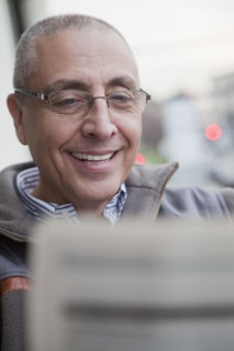 Hispanic senior man reading newspaper