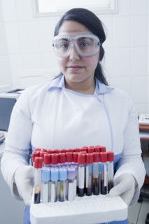 Hispanic scientist holding blood samples in test tube rack in laboratory