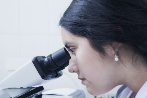 Hispanic scientist using microscope in laboratory