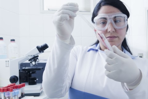Hispanic scientist pipetting blood sample in laboratory