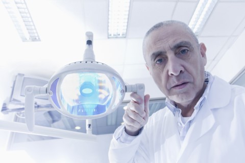 Hispanic dentist holding lamp in office