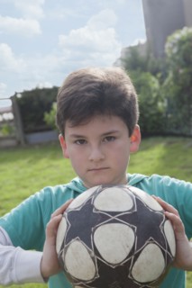 Hispanic boy holding soccer ball in backyard