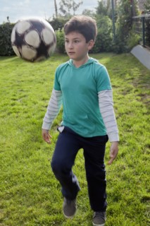 Hispanic boy juggling soccer ball in backyard