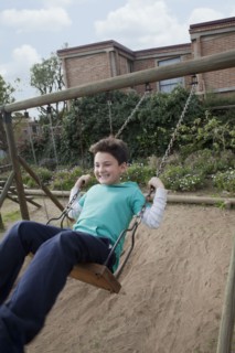 Hispanic boy playing on swing in backyard