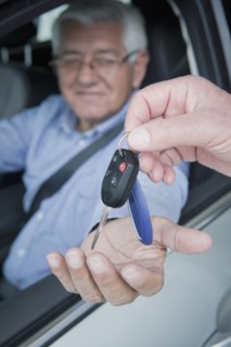 Hispanic car salesman handing keys to customer