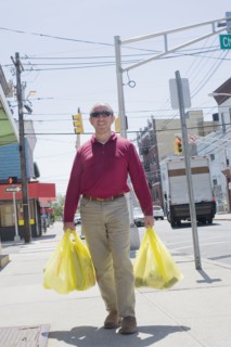 Hispanic man carrying shopping bags on city sidewalk