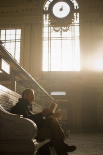 Hispanic man reading newspaper in train station