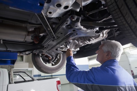 Older Hispanic mechanic repairing car in garage