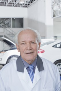 Older Hispanic mechanic standing in garage
