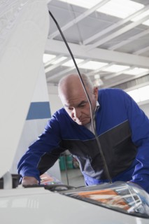 Older Hispanic mechanic repairing car in garage