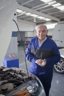 Older Hispanic mechanic working on car in garage