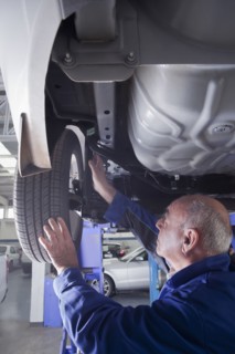 Older Hispanic mechanic repairing car wheel in garage