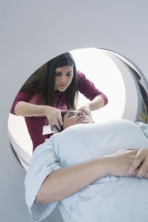 Hispanic nurse examining patient in MRI machine