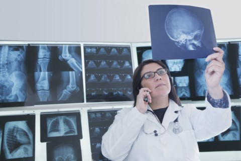 Hispanic doctor examining x-rays in hospital