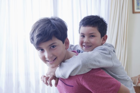 Hispanic boy carrying brother piggyback