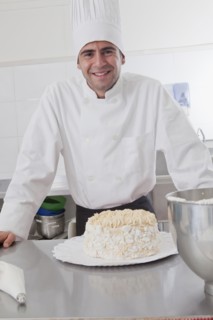 Smiling Hispanic chef posing with cake