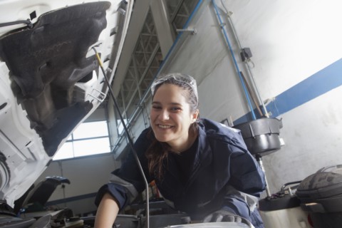 Smiling Hispanic mechanic repairing car engine