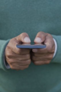 Hands of Hispanic man texting on cell phone