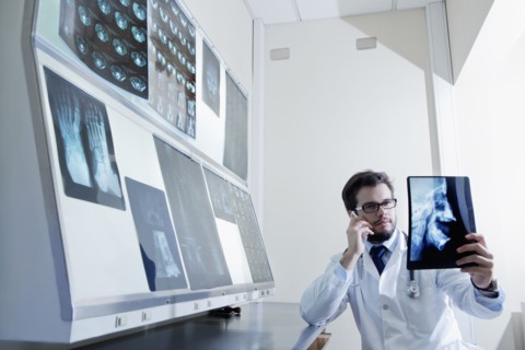 Hispanic doctor talking on cell phone examining x-ray