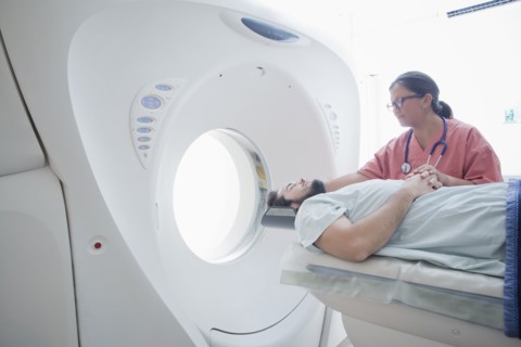 Hispanic nurse comforting patient at scanner
