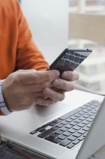 Hands of Hispanic man texting on cell phone