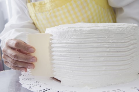 Hispanic woman shaping icing on cake