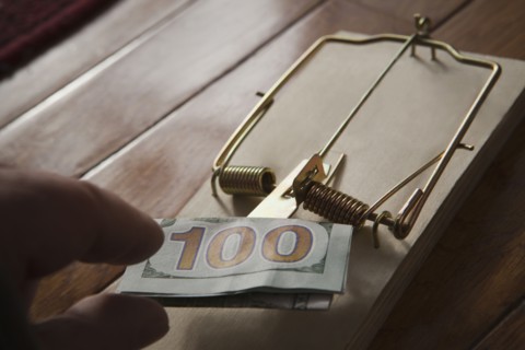 Hand of Hispanic man placing money in mousetrap