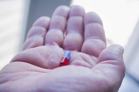 Hand of Hispanic man holding pill