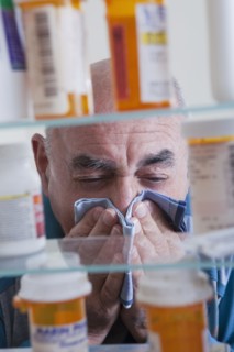 Hispanic man wiping nose near medicine cabinet
