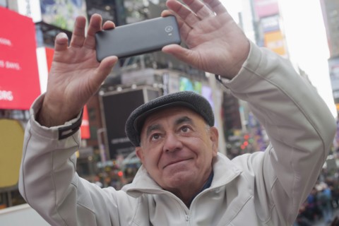 Hispanic man posing for cell phone selfie in city