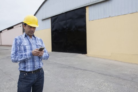 Mixed Race construction worker texting on cell phone