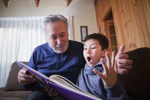 Hispanic grandfather and excited grandson reading book