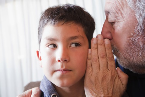 Hispanic grandfather whispering secret to grandson