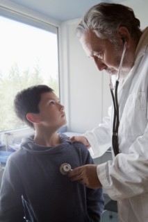 Hispanic doctor listening to chest of boy with stethoscope