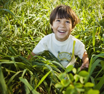 Grinning mixed race boy sitting in long grass