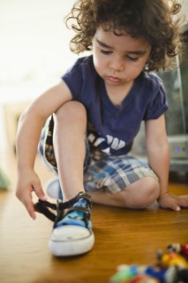Mixed race boy fastening shoes