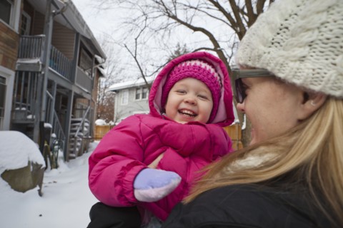Mother holding grinning girl in coat