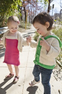 Caucasian girls holding hands on sidewalk