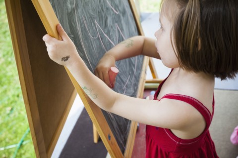 Girl drawing on blackboard easel