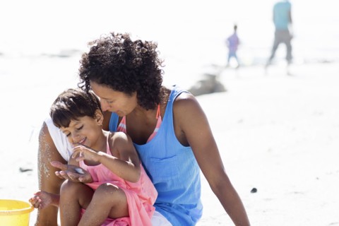Mixed race mother and daughter playing on beach