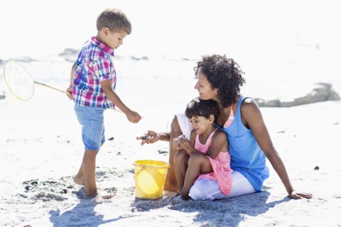 Mixed race mother and children playing on beach