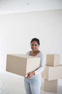 Mixed race woman carrying cardboard box in new home