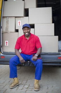 Black delivery man sitting with packages in van